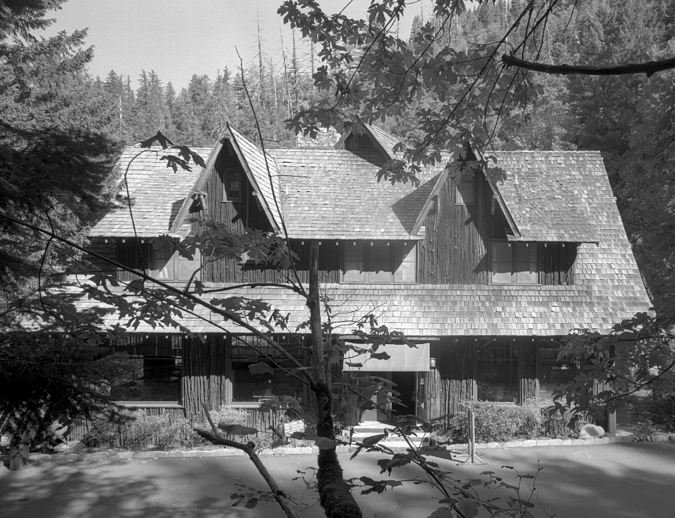 The Chateau at the Oregon Caves (1934) seen from street-level. The main entrance is under a canvas awning. Shed dormers broken up by gables. 